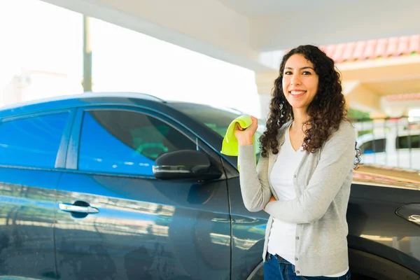 Portrait of a beautiful young woman drying her car with a microfiber after doing car wash chores