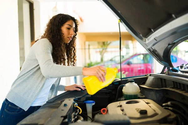 Attractive woman checking the engine and changing the oil of her car in the garage
