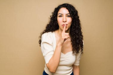 Dudaklarında parmakları olan ve bir sır ya da sessizlik isteyen İspanyol genç bir kadın. 