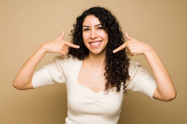 Büyük bir gülümseme ile beyaz dişlerini gösteren ve mutlu gülümseyen heyecanlı çekici bir kadın.