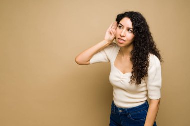 Güzel genç bir kadın elini kulağına koyup bir sır ya da dedikodu dinlemeye çalışıyor.