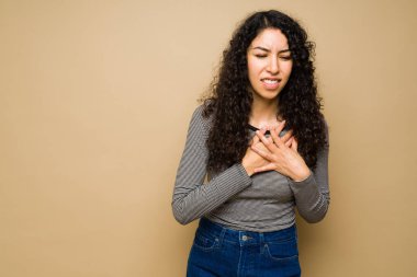Stresli genç bir kadın göğüs ağrısı çekiyor ya da stüdyo arka planında kalp krizi geçiriyor.