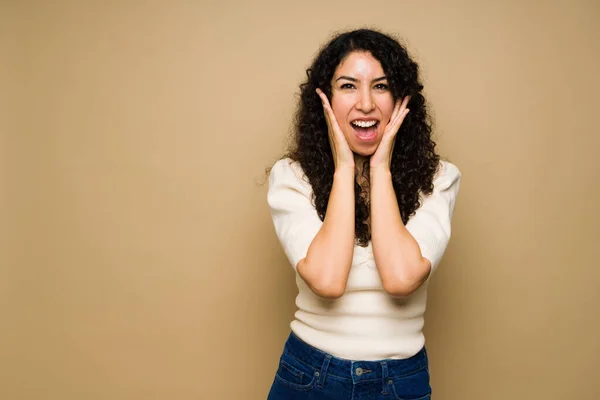 Surprised woman looking excited and shocked while screaming with happiness after hearing good news next to copy space