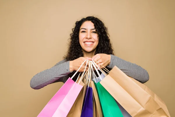 Portrait of an excited mexican woman showing a lot of shopping bags and looking very happy