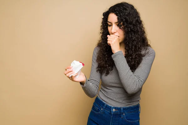 Worried sick young woman coughing blood and looking concerned about having cancer