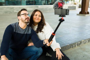 Smiling influencer couple filming a video blog and content with a camera for their social media and followers