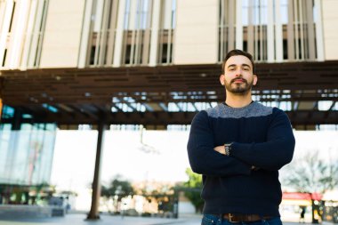 Handsome young man looking powerful while making eye contact posing outdoors in the city