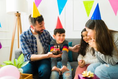 Happy parents with their young boy celebrating a birthday party with party hats while having fun