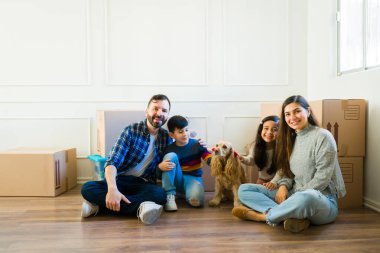 Happy family with little kids and dog happy about being home owners with a lot of boxes moving to a new house 