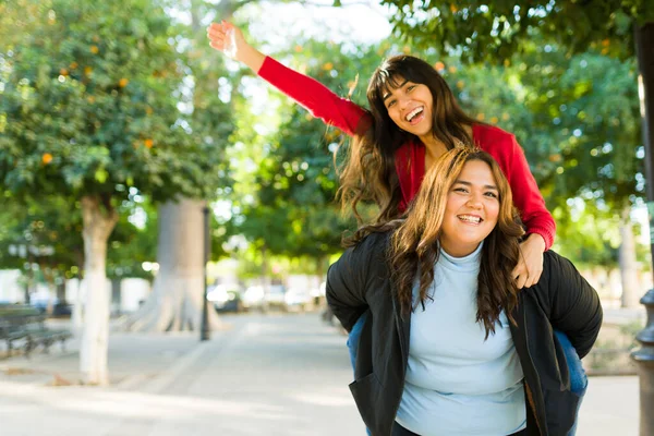 Cheerful Young Women Piggybacking Celebrating Beautiful Friendship Having Fun Outdoors — Stockfoto