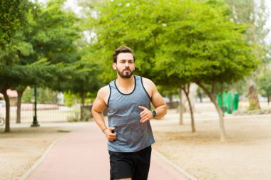 Fit young man with an active lifestyle going for a run in the park and exercising outdoors 