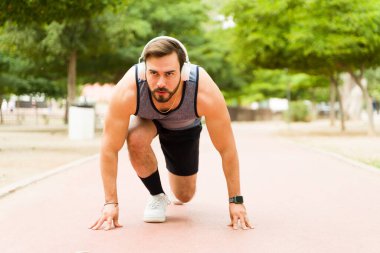 Determined young man in the ready set go position preparing to start running in the park