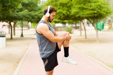 Profile of a handsome man doing stretching exercises preparing to start running at the park