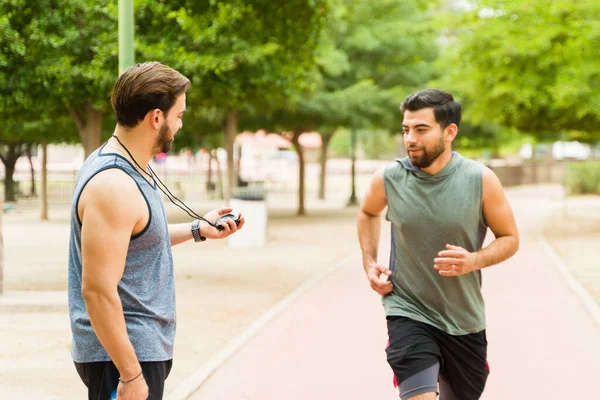 Fitness Coach Checking Time While Training Young Man Running Outdoors — Stock Photo, Image