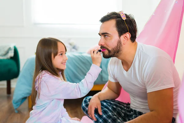 Caucasian father putting on lipstick and playing makeup games with his adorable little girl daughter