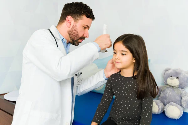 Adorable kid getting a medical exam with a pediatrician using an otoscope because of an ear infection