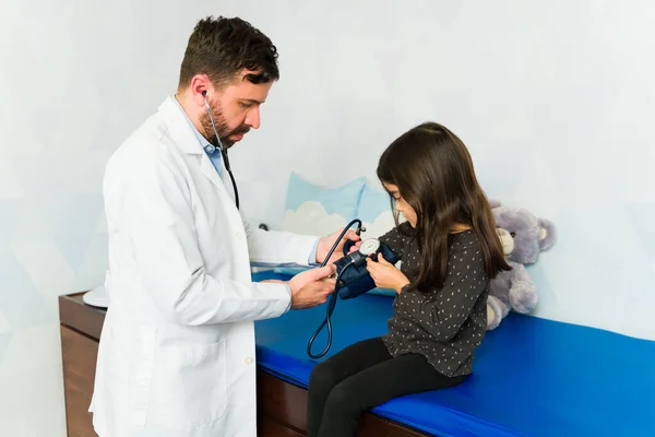 Pediatrician using a pressure gauge to check blood pressure during a medical check-up of a young kid