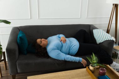 Exhausted depressed obese woman looking lonely lying on the sofa suffering from depression
