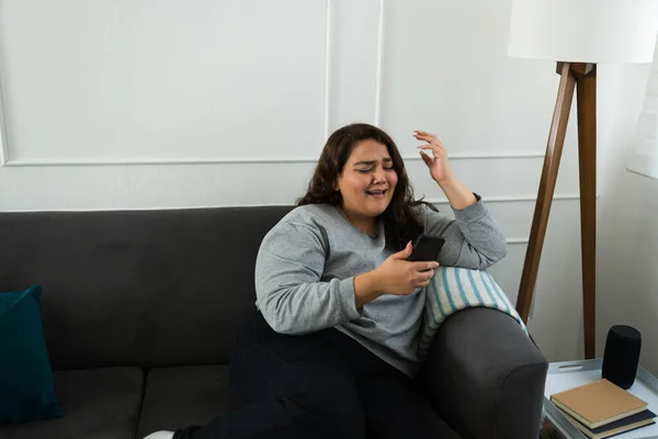 伤心的超重女人在家里哭泣着 一边用智能手机发短信 一边在伤心的分手后思念着她的男朋友 — 图库照片