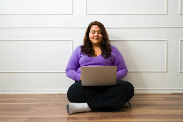 Smiling Latin Overweight Woman Sitting Floor Typing Laptop While Working — Stock fotografie