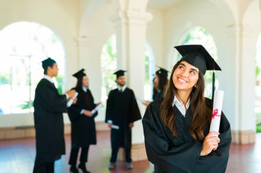 Thoughtful latin woman thinking about her future and having new ideas after getting her university diploma during graduation