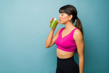 Profile of a fit athletic woman in activewear drinking her healthy green juice before working out 