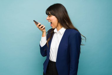Angry professional woman feeling upset and screaming while having work problems and talking on the phone