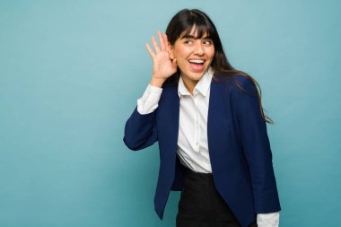 Happy attractive professional woman cupping her ear and trying to listen to a secret or work gossip 