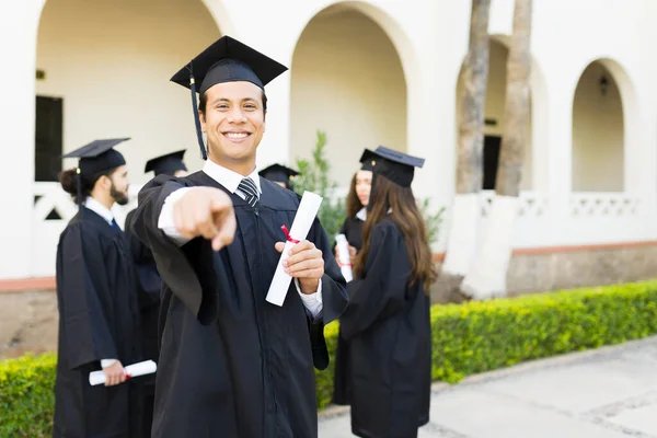 Jovem Latino Sorrindo Apontando Enquanto Mantém Seu Diploma Universitário Depois — Fotografia de Stock