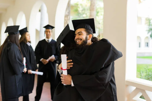 Smiling Young Man Hugging Friend Graduate Celebrating Graduating College While — Fotografia de Stock