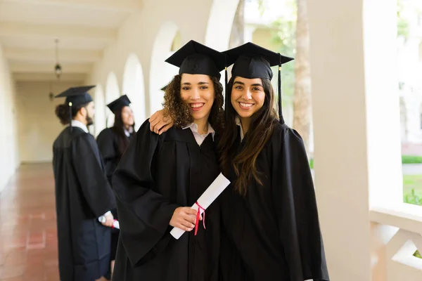 Portrait Beautiful Women Friends Wearing Graduation Gowns Hugging Receiving University — Foto de Stock