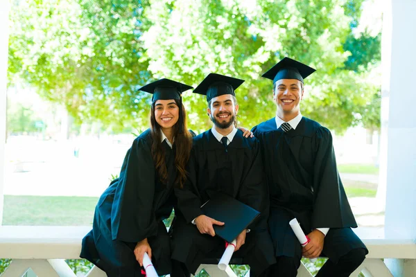 Attractive Friends Wearing Graduation Gowns Caps Smiling Making Eye Contact — Fotografia de Stock