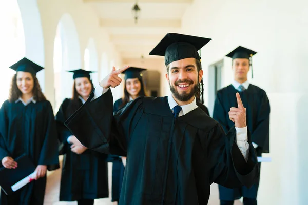 Happy Attractive Latin Man Pointing His Graduation Gown Cap While — Fotografia de Stock