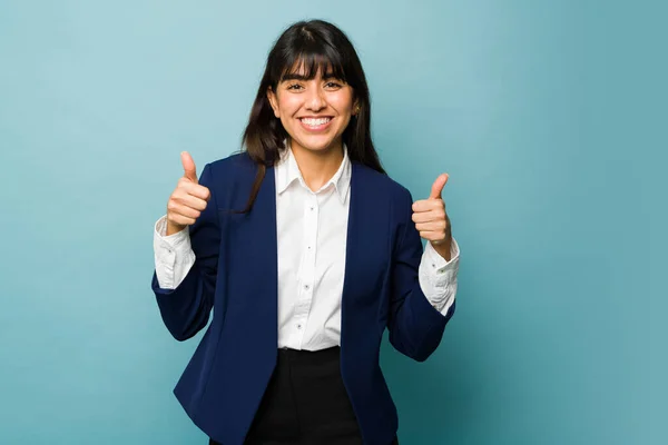 Successful hispanic business woman doing a thumbs up looking excited while enjoying working
