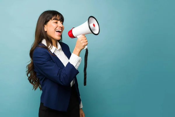 Cheerful business woman screaming a work message using a megaphone and saying good news at her job