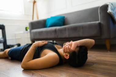 Tired young man at home lying on the floor and resting looking exhausted after finishing his workout exercises 