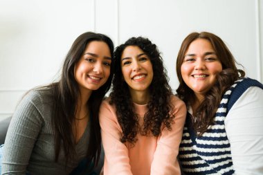 Attractive hispanic women friends in their 20s smiling looking happy while hanging out together 