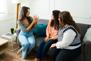 Happy young woman showing her engagement ring to her excited best friends while hanging out together