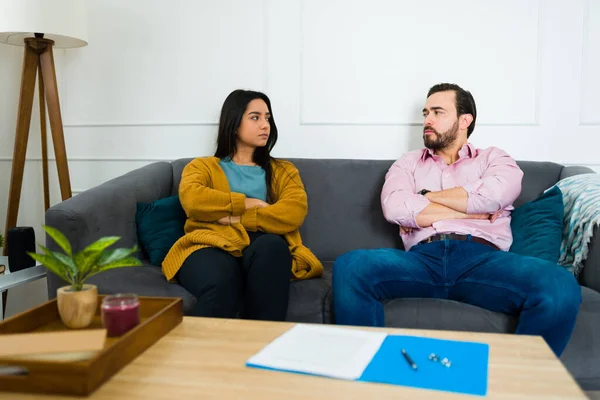 怒气冲冲的年轻女子和满脸愁容的男子坐在沙发上 想着要签署离婚协议 — 图库照片