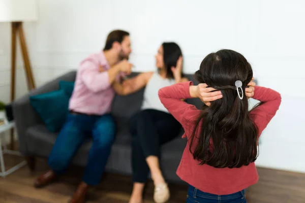 怒った両親を見ながら彼女の耳を覆う動揺した少女と娘の後景彼女の怒っている両親を見ながら家で戦う — ストック写真