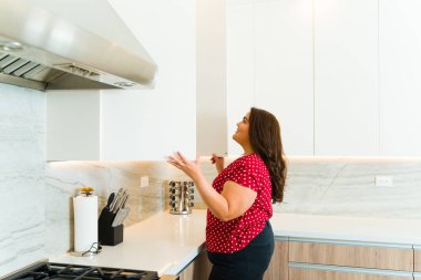 Mutfakta yemek yapmaya hazırlanırken beyaz granit dolabı açarken gülümseyen güzel kadın.