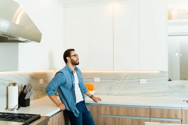 stock image Relaxed caucasian man looking happy smiling while relaxing in his beautiful sunny white luxury kitchen