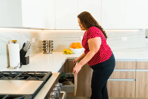 一名体重超标的年轻女子打开花岗岩台面抽屉 准备在豪华厨房做饭的侧视图 — 图库照片