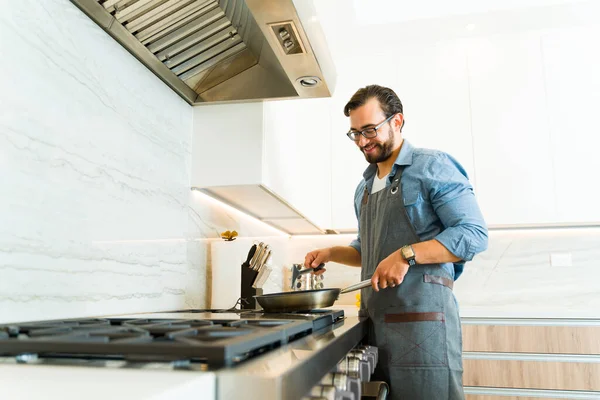 Homem Caucasiano Cozinhar Almoço Fogão Aço Inoxidável Enquanto Sorrindo Olhando — Fotografia de Stock