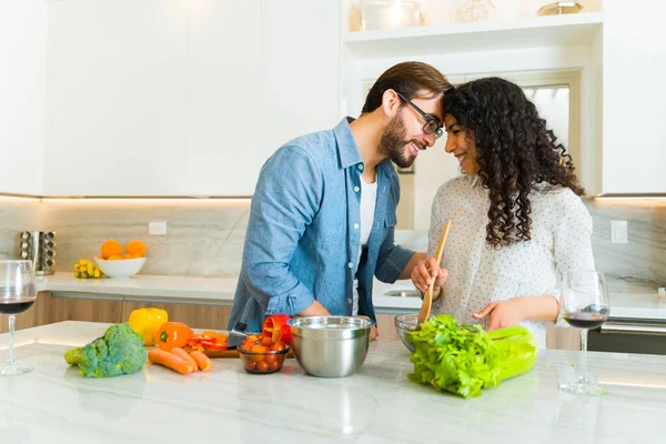 这对可爱的夫妻面带微笑 即将在一个漂亮的厨房里接吻 同时一起做着健康的食物 — 图库照片