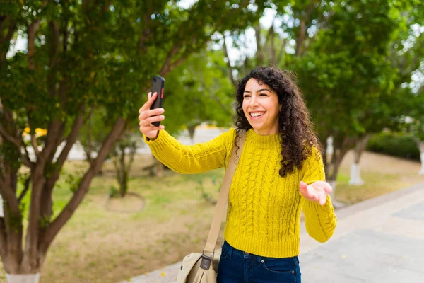 当一个迷人的女人在户外散步的时候 用她的智能手机与朋友和家人进行在线视频通话时 她兴奋极了 — 图库照片