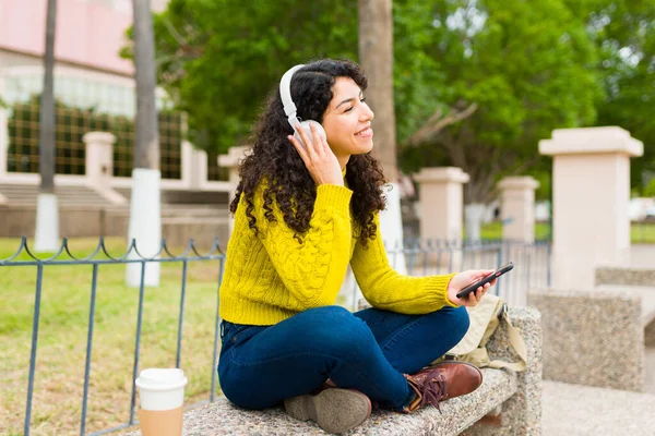 在公园里 一个快乐而有魅力的女人 带着耳机听着音乐 看上去很开心 很放松 — 图库照片