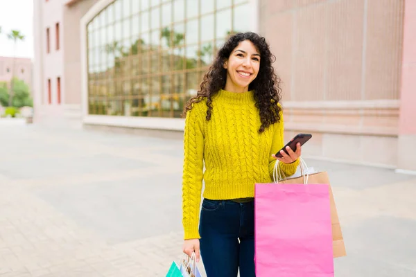 Attraktiv Kvinna Håller Smartphone Med Hel Del Shoppingväskor Ser Glad — Stockfoto