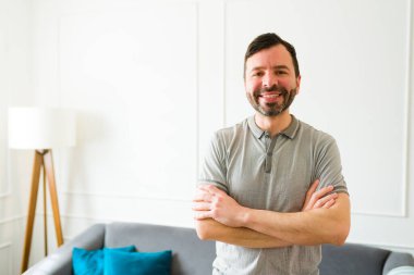 Yeni evinde göz teması kurarken mutlu ve rahatlatıcı bir şekilde gülümseyen 30 'lu yaşlarında çekici beyaz bir adam.