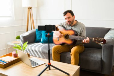 Yetenekli bir sanatçı evinde gitar çalarken kamerayla video klip çekiyor.